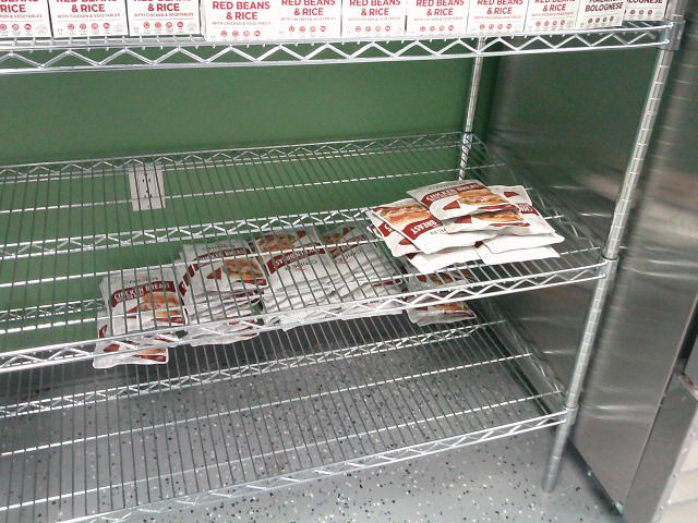 Boxes of red beans and rice on the top shelf. The middle and bottom shelf has pouches of chicken breasts